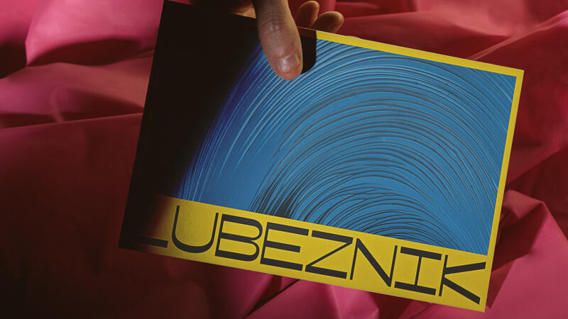 Hand holding a postcard with Lubeznik logo at bottom