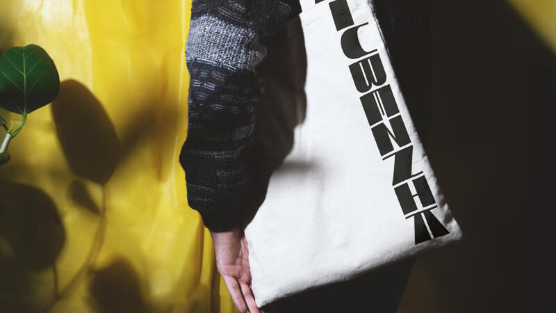 Lubeznik logo on a tote bag draped over someone's shoulder