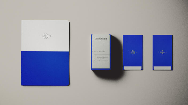 Vested World notebook and business cards featuring logo and brand colors